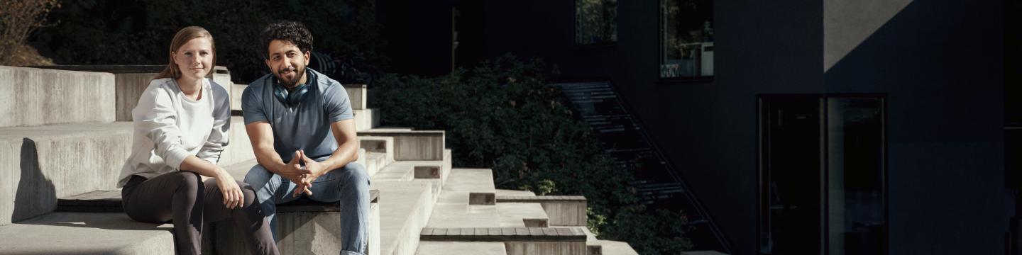 Smiling man and woman sitting on concrete steps