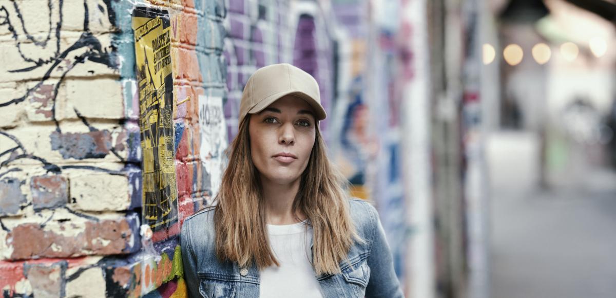 A woman stands in front of a wall 