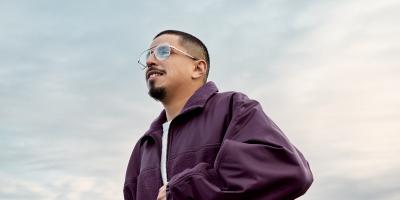 man in purple jacket looking out in front of a blue sky