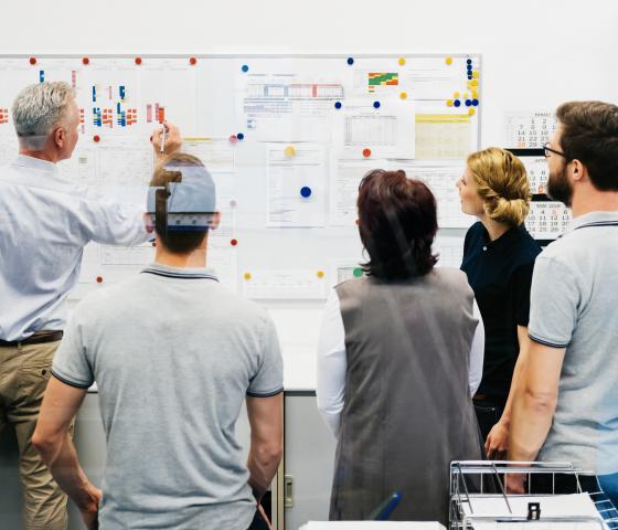 SCM Production group of people looking at white board