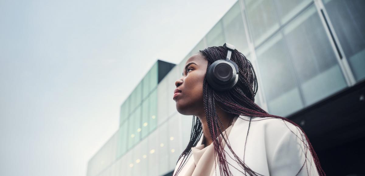 Woman with headphones in urban business setting looking up