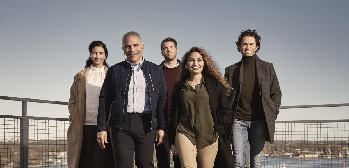 A group of five adults walking on a roof terrace