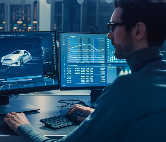 Man looking at computer screen displaying a modern car