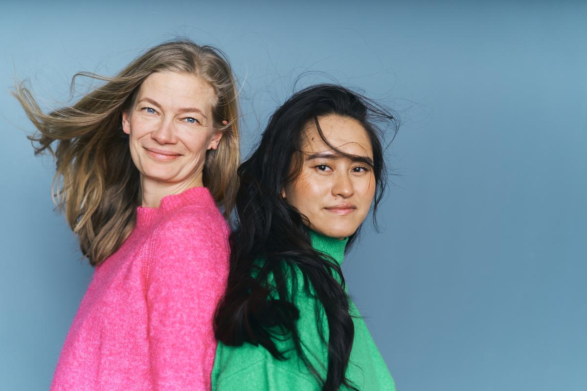Two persons looking into the camera with wind in their hair.