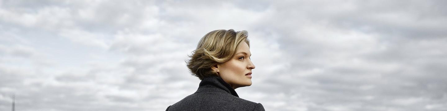 Woman on rooftop looking out towards cloudy sky