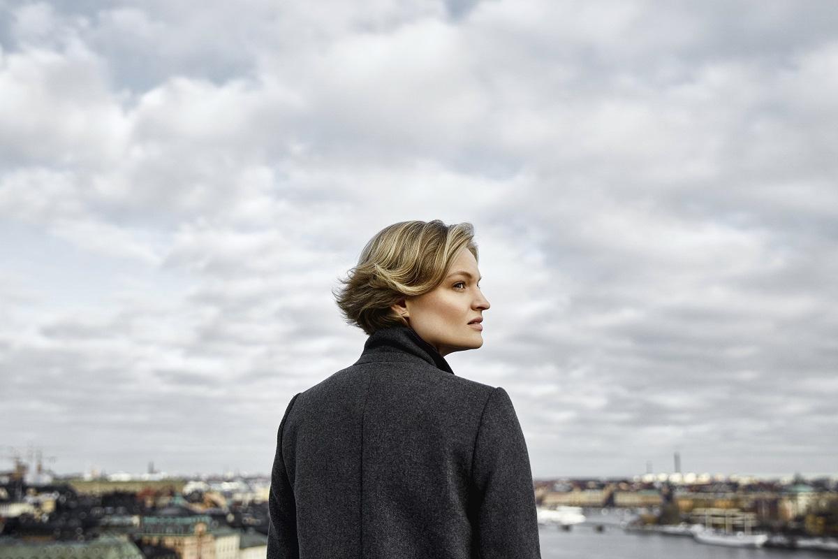 Woman on rooftop looking out towards cloudy sky