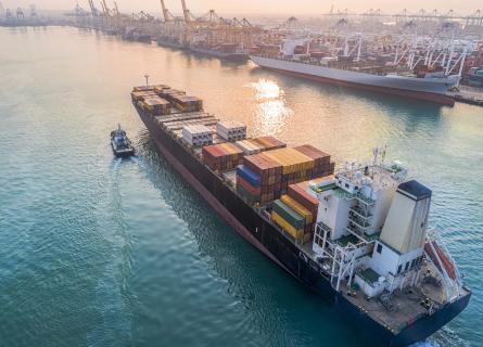container ship arriving to harbour with tug boat
