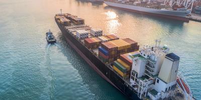 container ship arriving to harbour with tug boat
