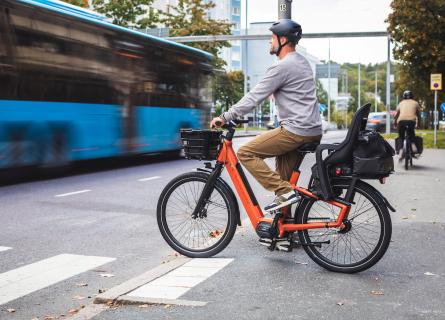Man on an orange bicycle in the city