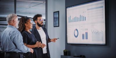 Three people looking at screen with dashboard.