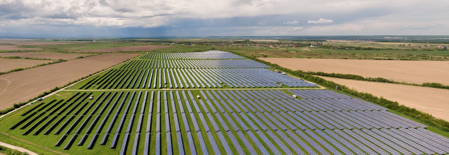 Aerial view of a Danish field of PV solar panels under a partly cloudy blue sky