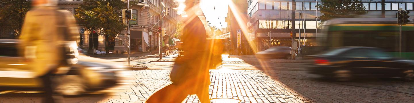 people walking and cars driving in a city during sunrise