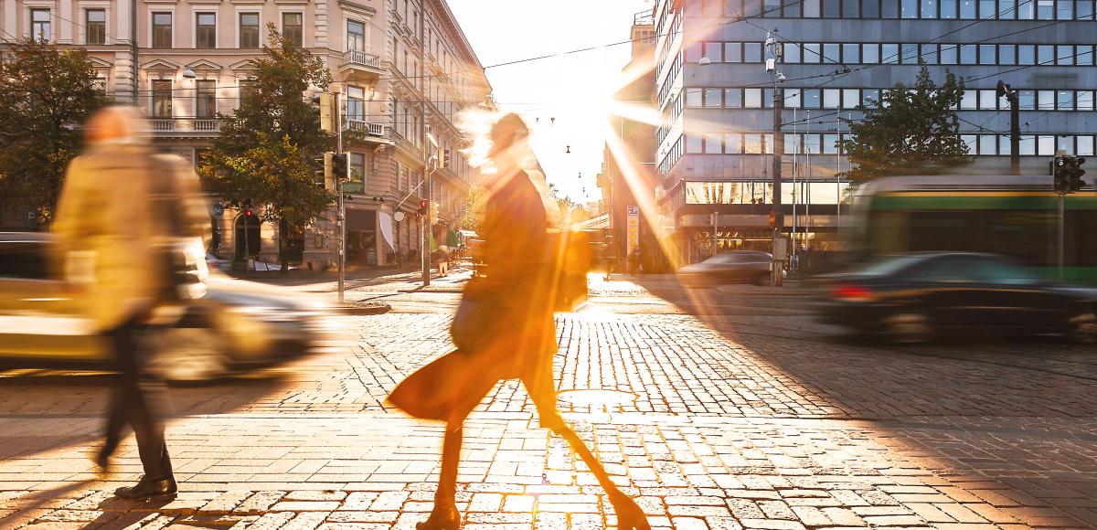 people walking and cars driving in a city during sunrise