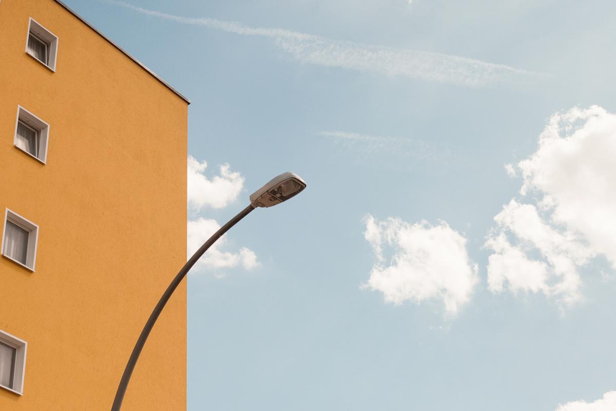 the facade of a yellow house and a street lamp on the left side