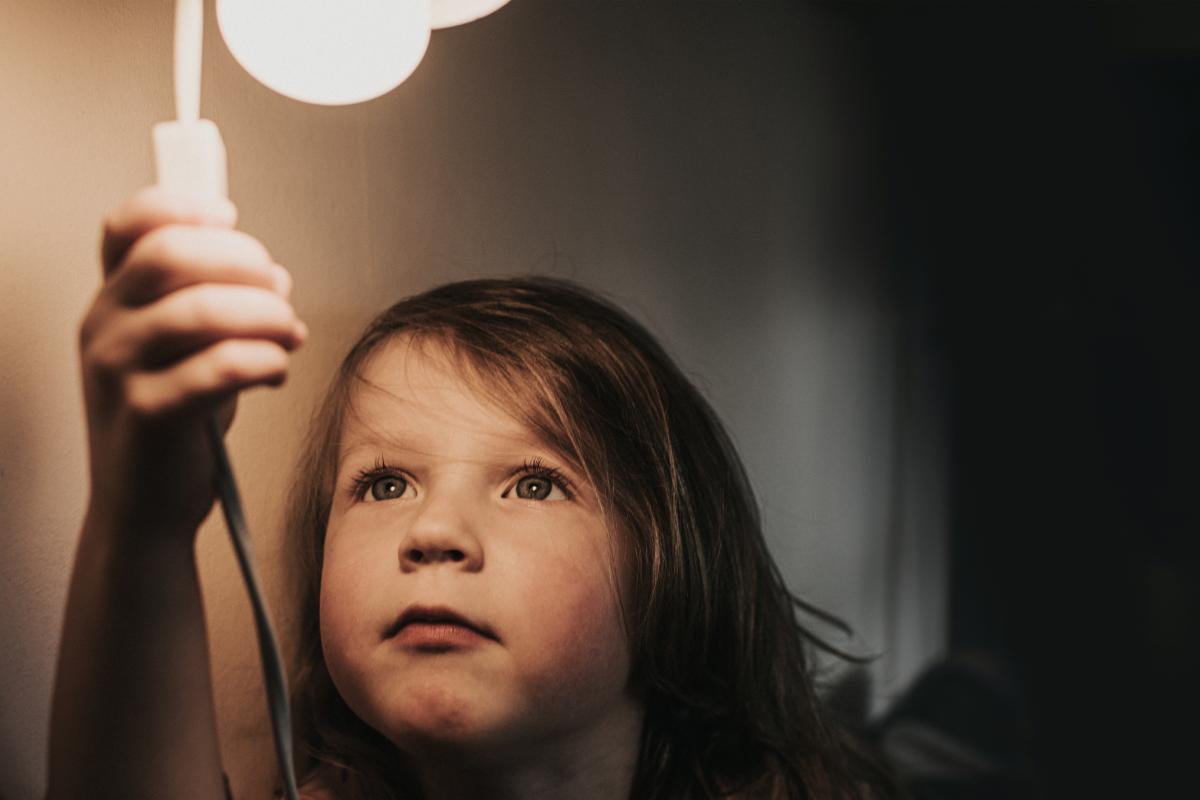 Small child reaching up to switch on light