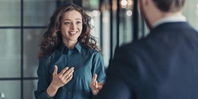 Smiling woman in lomg curley hair talking to a man