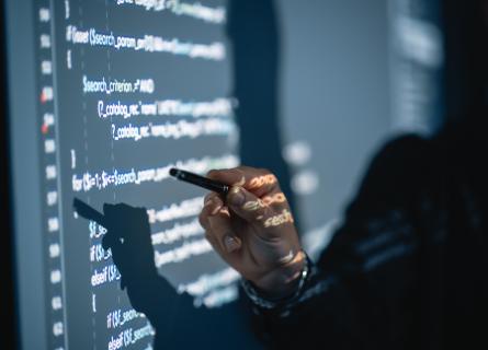 A man pointing at a wall with code projected onto it