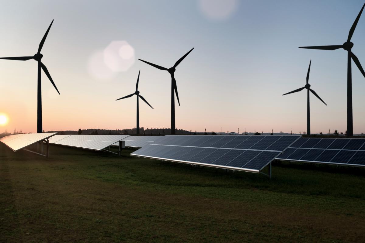 Silhouettes of wind turbines and solar panels on a morning sky