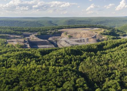 Aerial view of open pit mine surrounded by forest