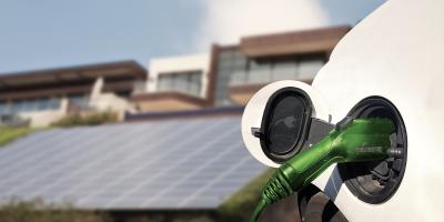 Electric vehicle charging in front of house with solar panels