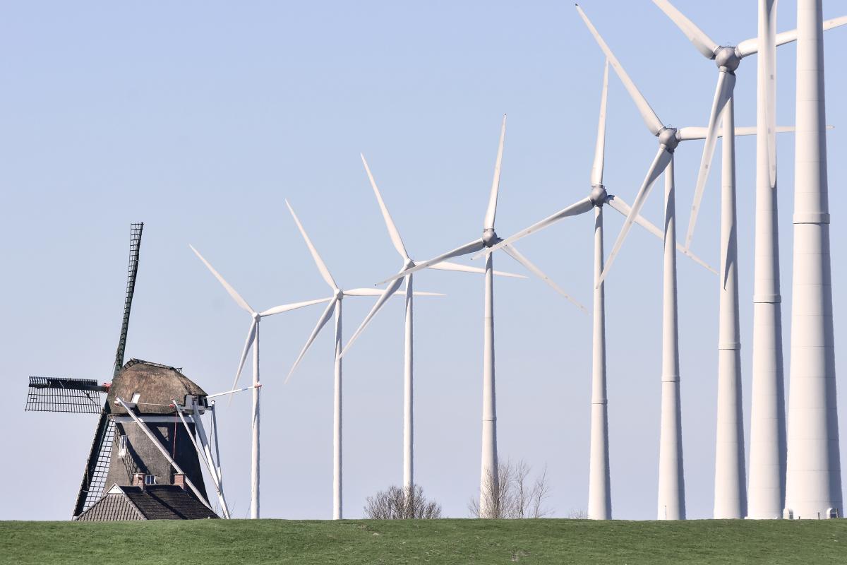 Windmill and a row of wind turbines in the Netherlands