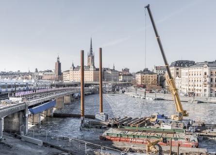 Construction works in the waterfront, rail bridge and city in the background