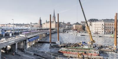 Construction works in the waterfront, rail bridge and city in the background