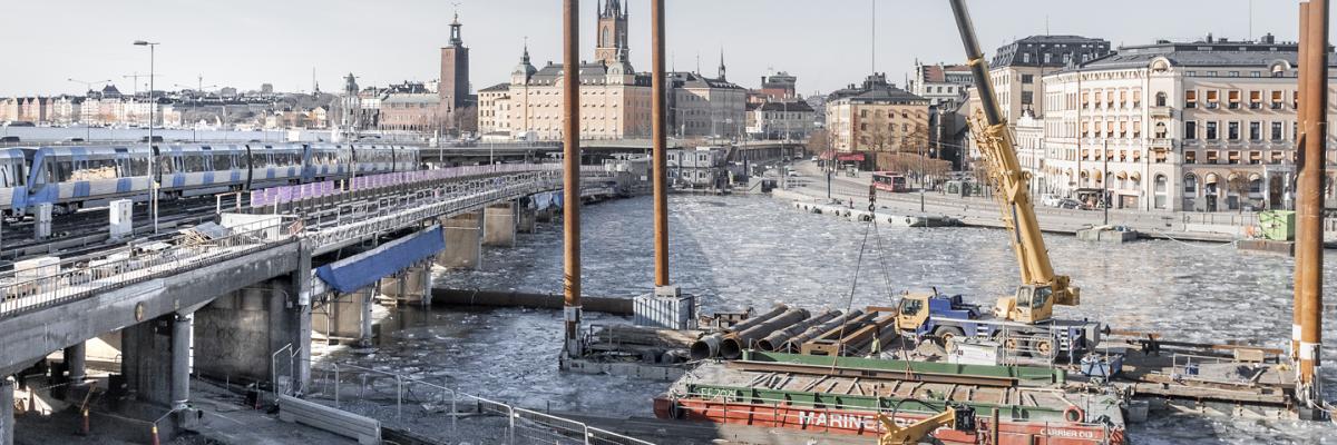 Construction works in the waterfront, rail bridge and city in the background