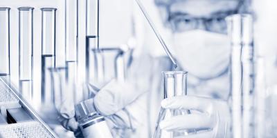 Scientist in a lab holding a glass bottle and a dropper