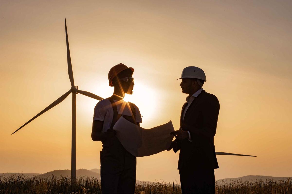Engineer and project manager talking in front of wind power plant