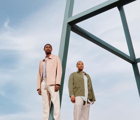 Expansive light blue-sky backdrop, with a man and a woman in the foreground standing next to a metal structure