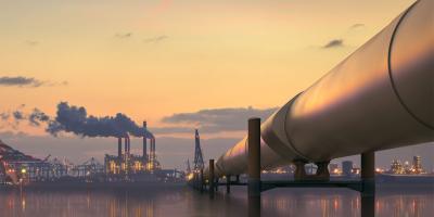 Oil pipeline in industrial district with factories at dusk