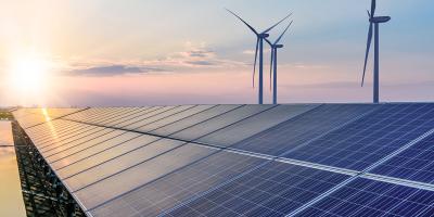 Solar panel row in front of wind rotors by setting sun