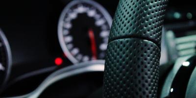 close up of black leather steering wheel inside vehicle