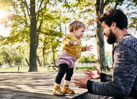 Small child jumping into arms of bearded man