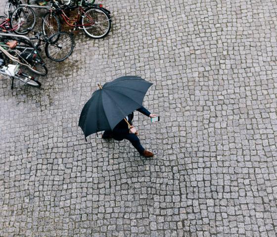 a person walking with an umberella while looking at the phone