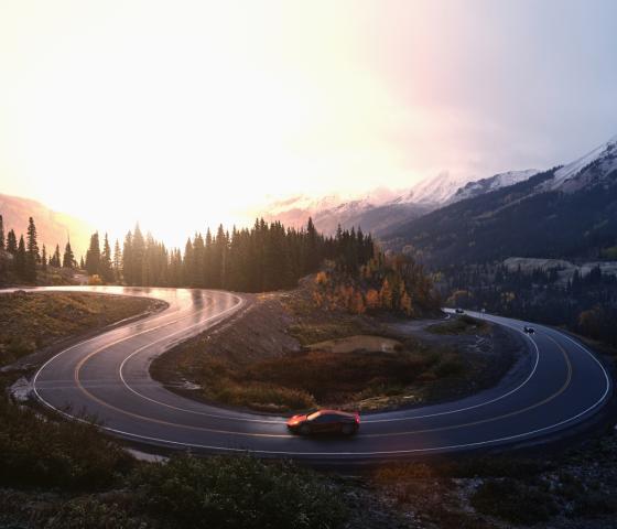 Red sports car driving on winding road