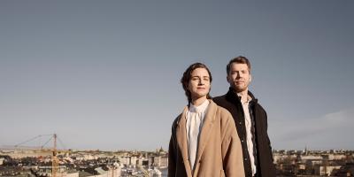 A man and a woman standing on a rooftop looking out over the city
