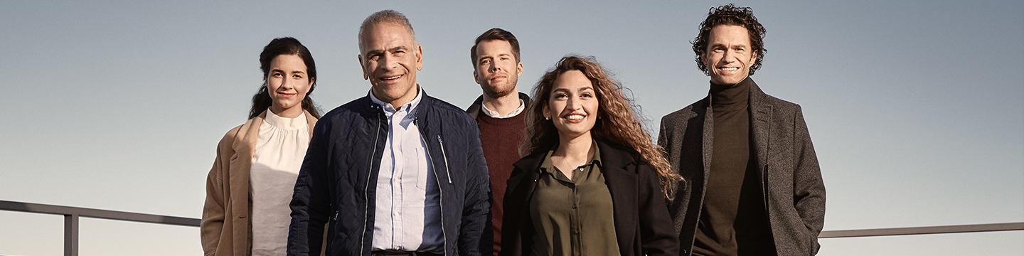 A group of five adults walking on a roof terrace 