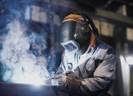 person welding wearing a helmet and creating a cloud