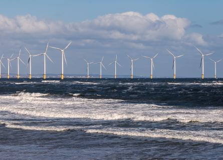 Lines of offshore wind turbines in the rolling surf off the North Sea coast