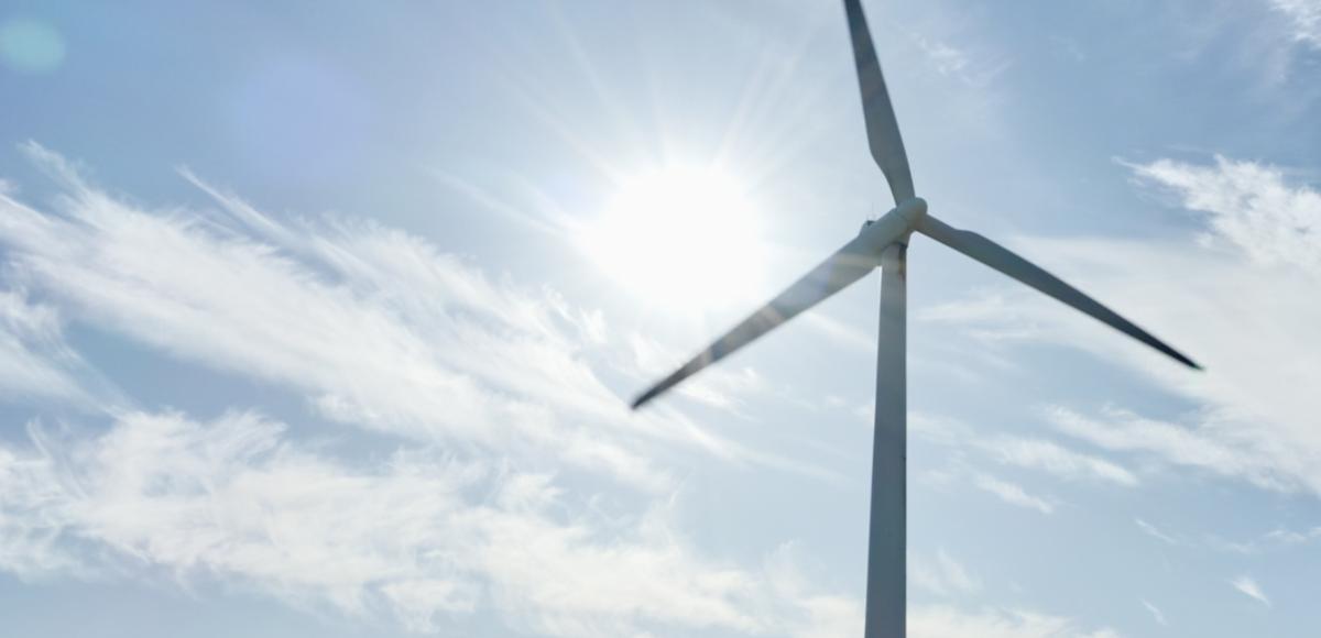 Expansive light blue-sky backdrop, with a wind turbine in the foreground