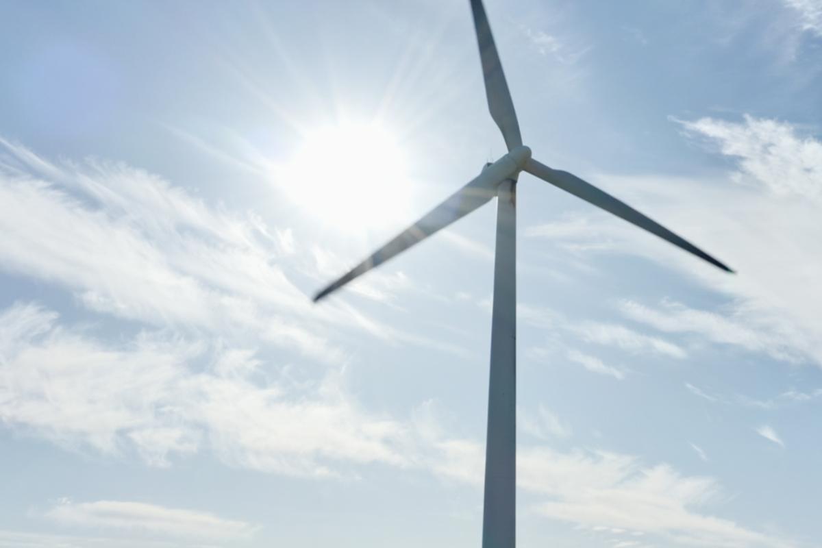 Expansive light blue-sky backdrop, with a wind turbine in the foreground