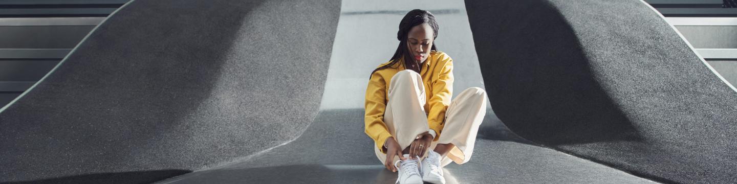 Woman tying shoelaces, white trainers, yellow jacket