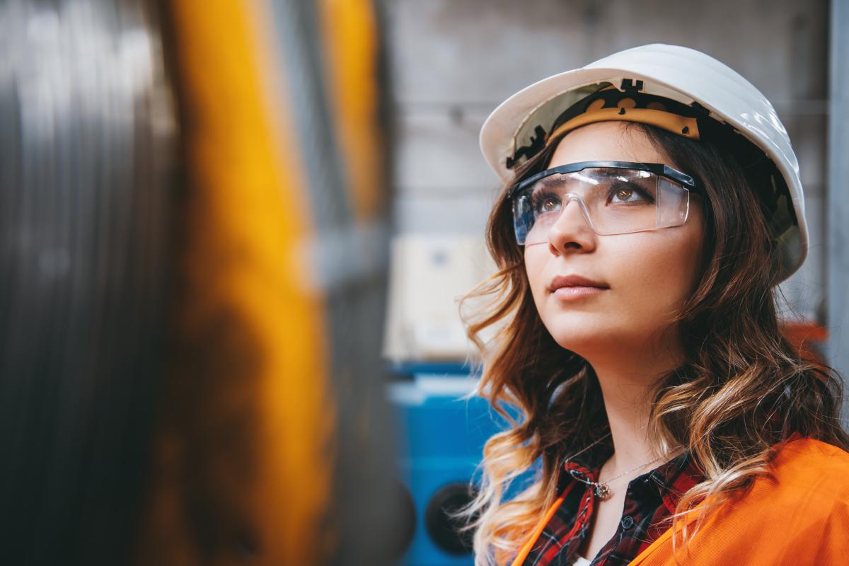 Young businesswoman white helmet googles industrial environment