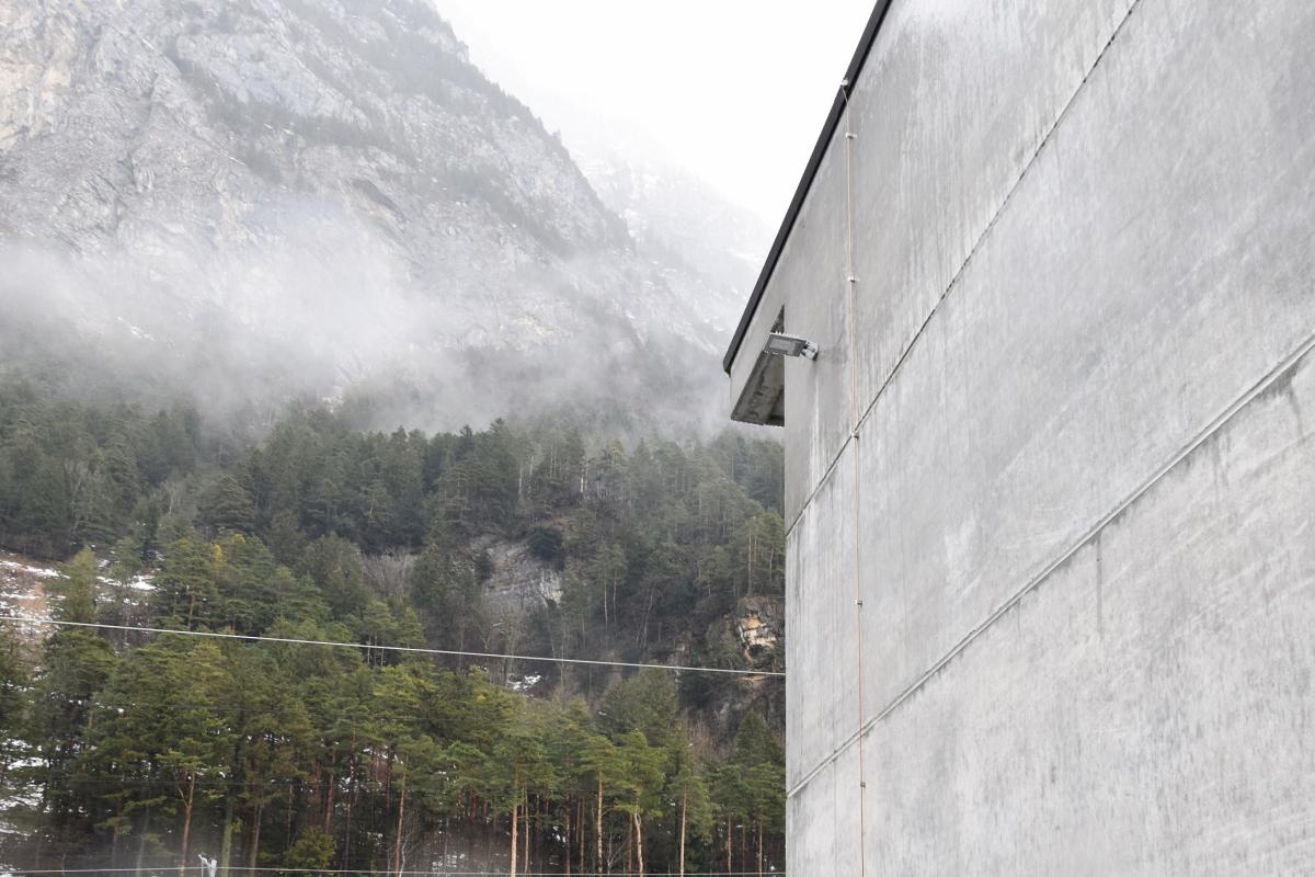 a concrete wall and in the background you can see forest and mountains